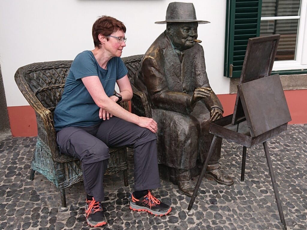 Eine Frau sitzt neben einer malenden Bronzestatue von Winston Churchill