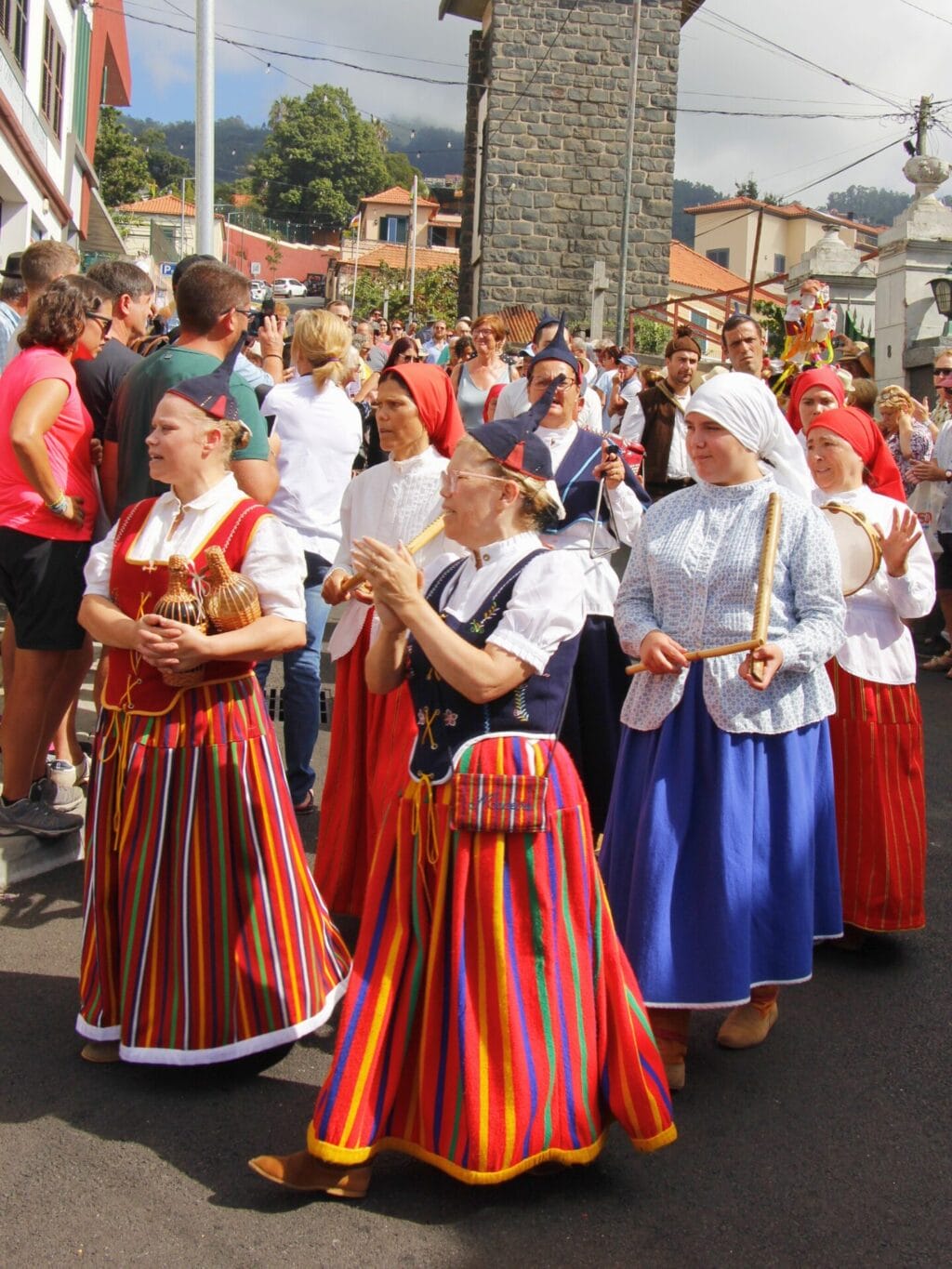 Frauen in farbenfroh gestreiften traditionellen Trachten gehen an einem Umzug auf der Strasse.